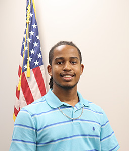 Headshot of Micah Austin in front of an American flag.