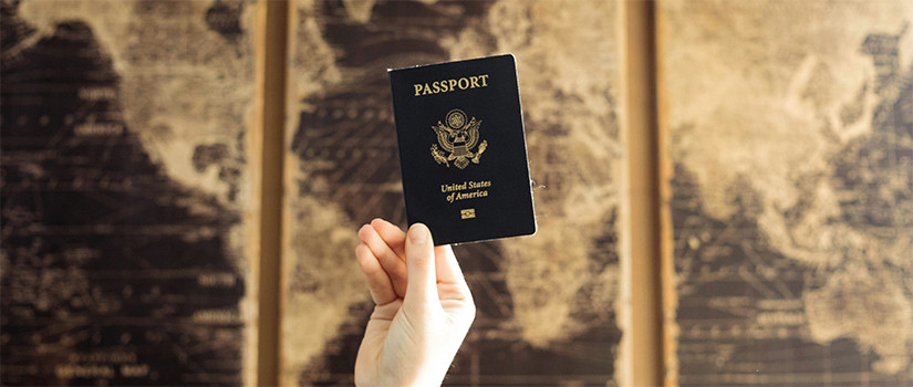 person holding a U.S. passport in front of a world map