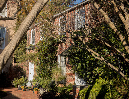 Old brick building that used to be slaves quarters surrounded by vines and trees