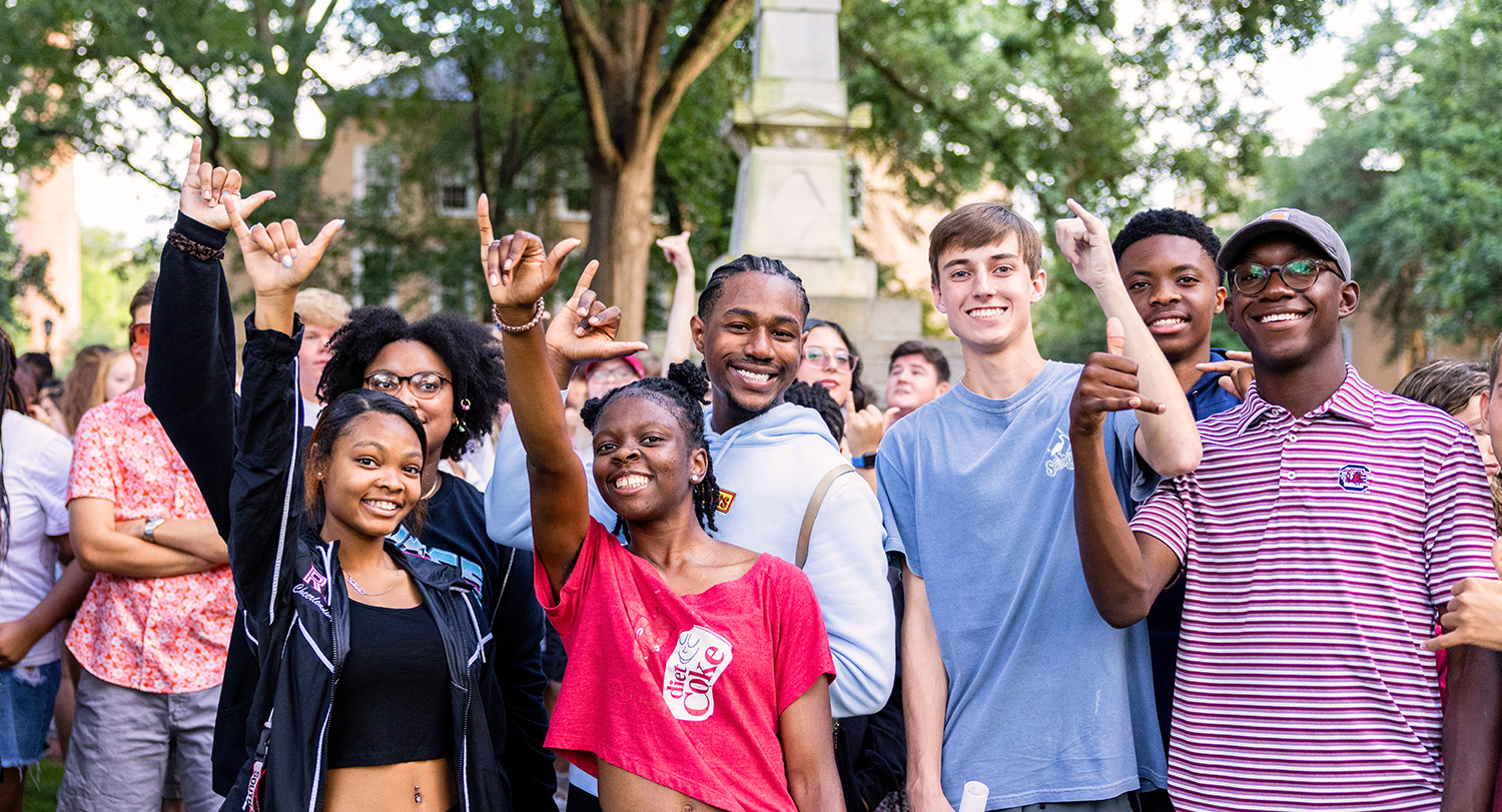 Students gathered together on the horseshoe giving a spurs up gesture.