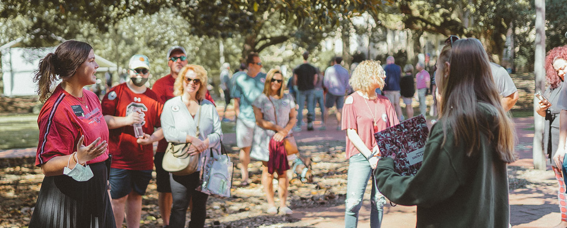 a student speaks to a group of visitors on an outdoor tour