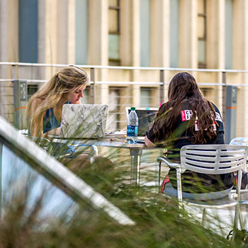 Students studying together at an outdoor table.