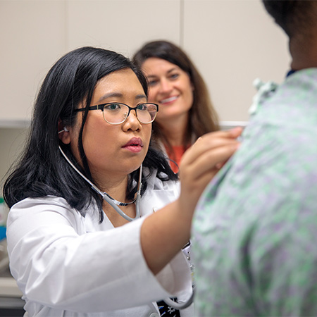 Medical student listening to a patient with a stethoscope.