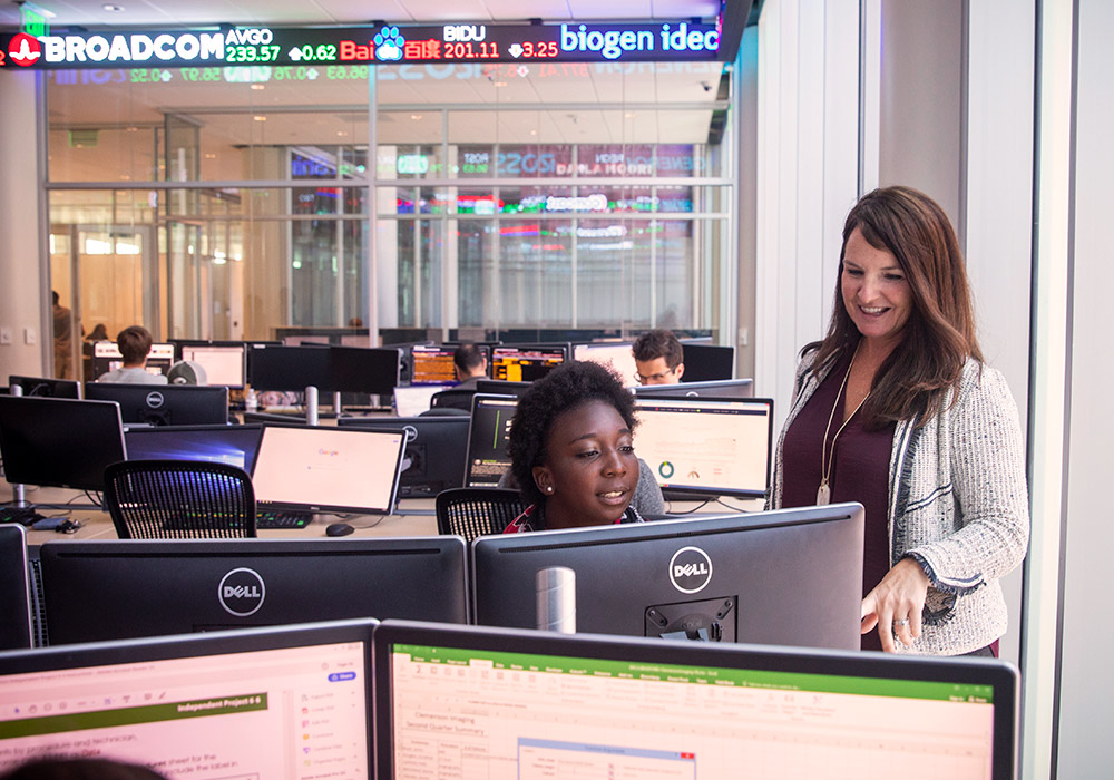 Porfessor talking with a student in a computer lab. 