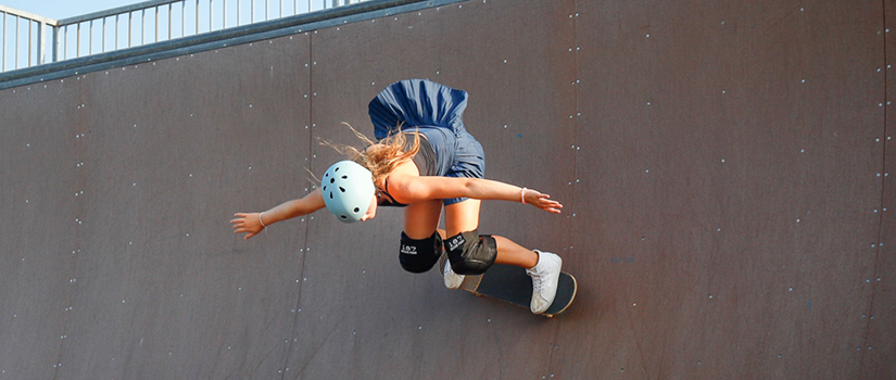 Chase Barclay rides a skateboard on a large ramp, wearing a helmet and protective pads.