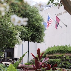 Photo that shows the Russell House building artistically peaking throw trees and brush