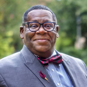 An outdoor headshot of Rex Tolliver wearing a suit and a bowtie.