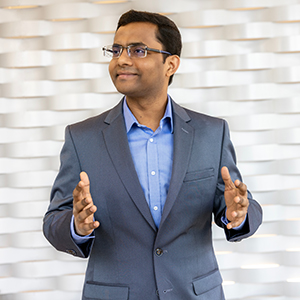 Sanjib Sur stands in front of a textured wall. 