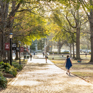 A photo of the sun setting on the Horseshoe brick walk with students walking.