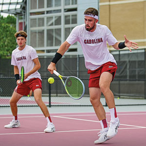 The two mid-game. One is hitting the ball with his racquet.