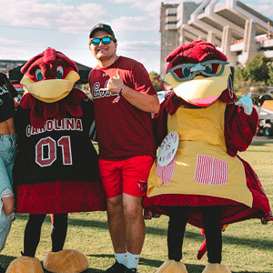 Man poses with Cocky and Cocky's mom. 