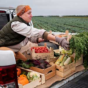 Fresh fruits and vegetables are passed between two adults in a rural community. 