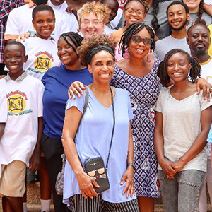 MInuette Floyd poses with students and teachers in front of a school library in Ghana.