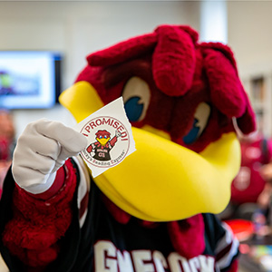 Cocky holds up sticker reading 