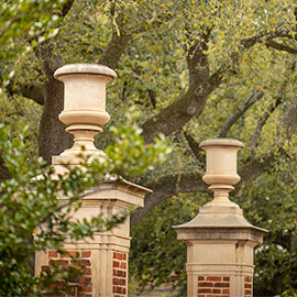 Two gates separated by greenery welcoming visitors to campus