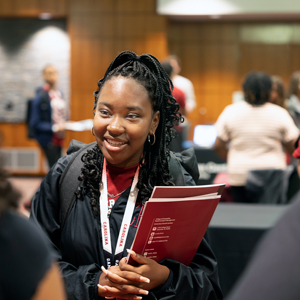 Summer seniors participant holds folders and talks to people at a table