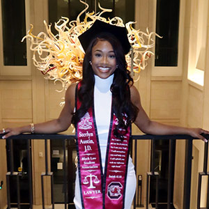 Sterlyn Austin in law school regalia poses in the law school